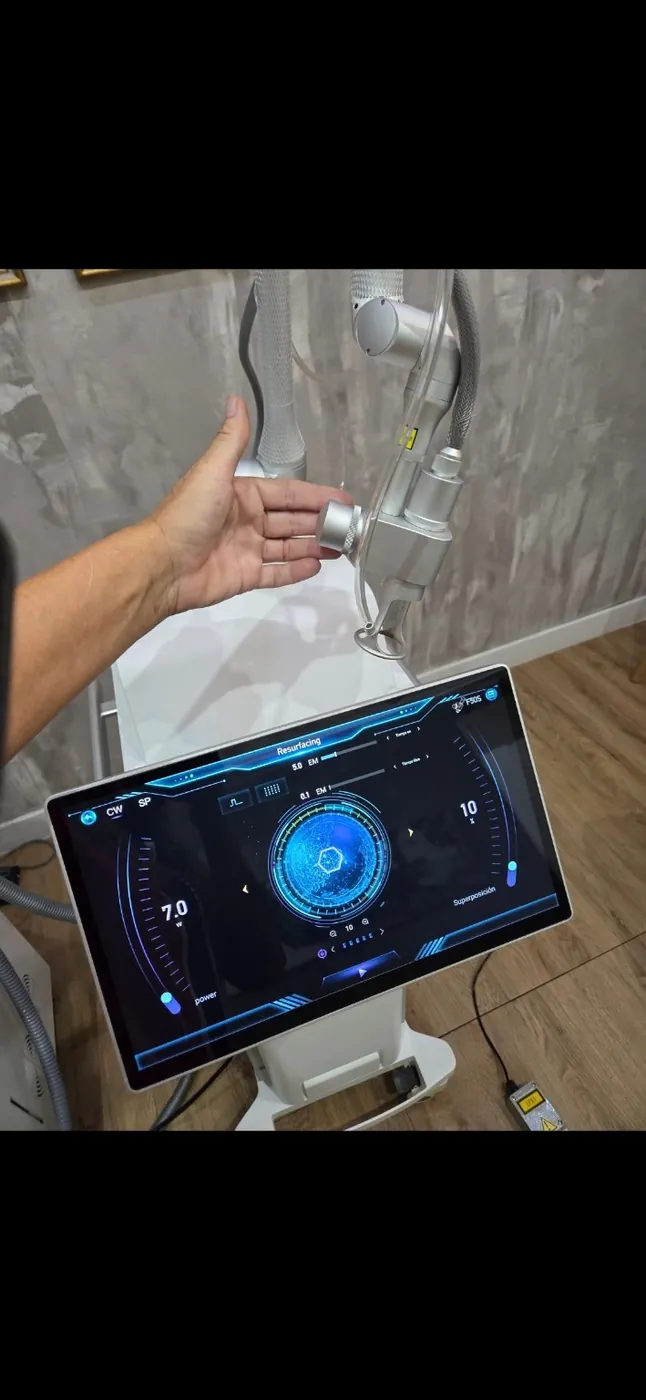 Mano sujetando el brazo articulado del 800 Fractional CO₂, con la pantalla al fondo